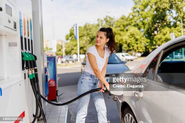 mujer molesta reabasteciendo el tanque de gasolina en la bomba de combustible - gasoline fotografías e imágenes de stock