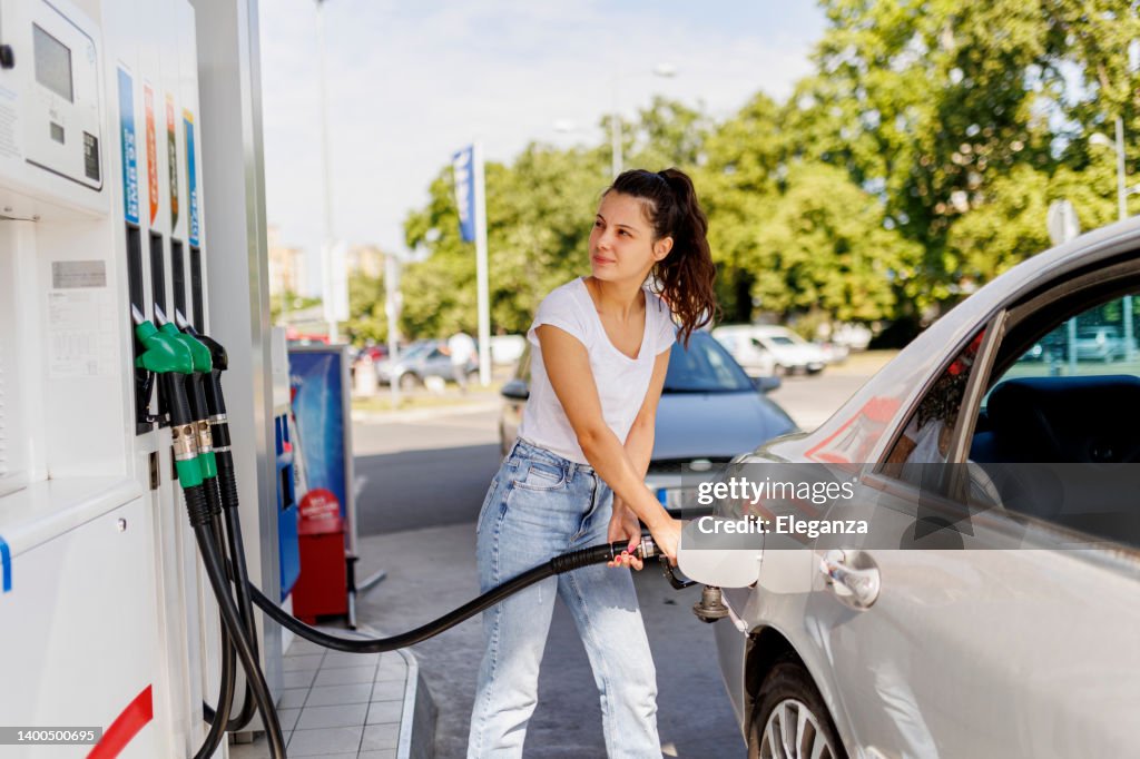 Upset woman refueling the gas tank at fuel pump