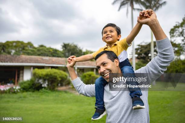happy father playing outdoors with his son and carrying him on shoulders - povo espanhol e povo português imagens e fotografias de stock