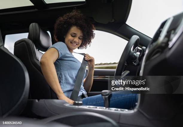 female driver fastening her seat belt in her car - seatbelt stock pictures, royalty-free photos & images