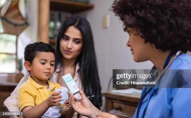 doctor giving prescription medicine to a boy while making a house call - kids call 911 stock pictures, royalty-free photos & images