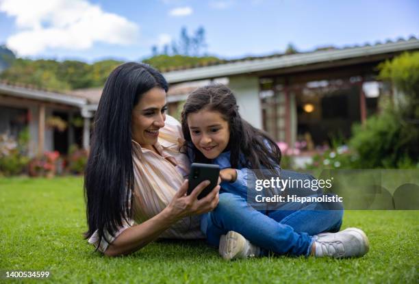 mother and daughter outdoors watching videos on a cell phone - colombia land stock pictures, royalty-free photos & images