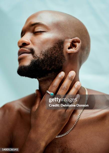 african man closed eyes looking away from the camera and touching his neck. he is wearing jewelry and has a beard. an african model with clear skin - man eyes closed stock pictures, royalty-free photos & images