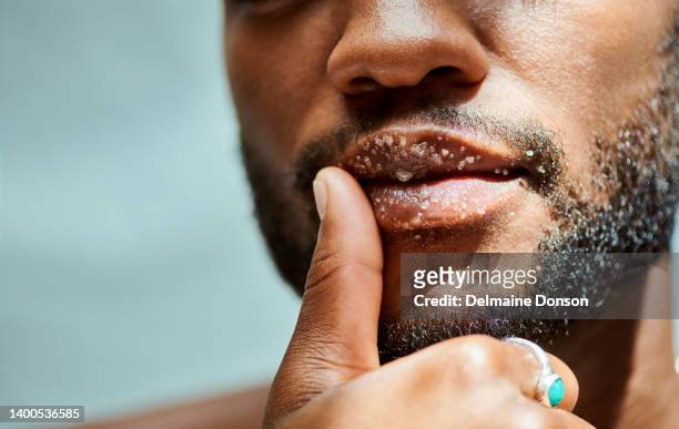 afrikanisches lippenpeeling, das männliche modell hat einen bart. er ist ohne hemd und trägt einen ring. der mann steht im raum mit einem isolierten studiohintergrund - hautpeeling stock-fotos und bilder