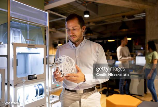 business man working at a creative office and holding a 3d printed model - 3d human model stockfoto's en -beelden