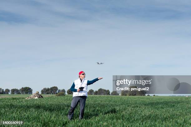 a drone pilot lands the aircraft on his hand in a cereal field. - agronomist stock pictures, royalty-free photos & images