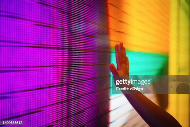 close up of a kid's hand touching illuminated and multi-coloured led display screen, connecting to the future concept - plasma stockfoto's en -beelden