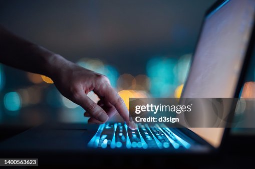 Close up of woman's hand typing on computer keyboard in the dark against colourful bokeh in background, working late on laptop at home Close up of woman's hand typing on computer keyboard in the dark against colourful bokeh in background, working late on laptop at home