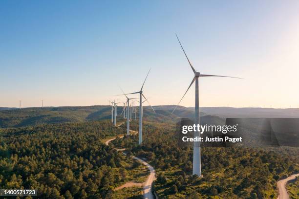 a row of wind turbines in rural spain towards sunset - energia eolica foto e immagini stock