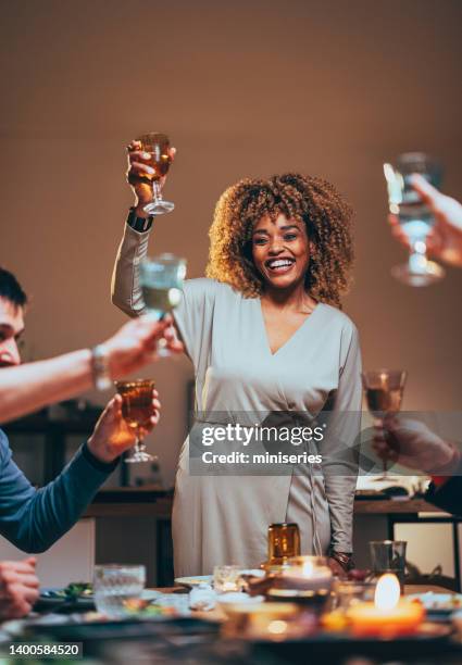 glückliche frau, die während einer dinner-feier mit einem glas wein anstößt - woman holding champagne stock-fotos und bilder