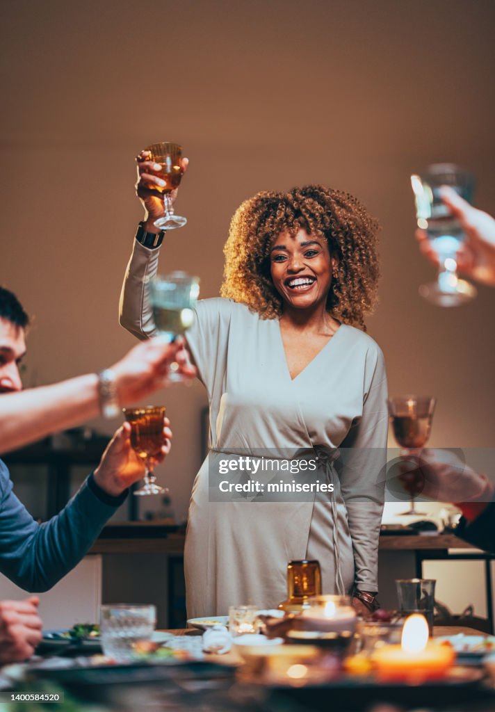 Mulher feliz brindando com uma taça de vinho durante uma celebração de jantar