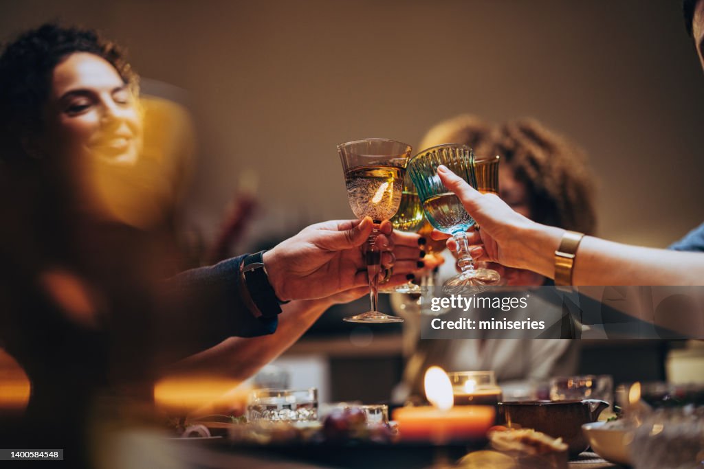 Freunde, die während einer Dinner-Feier mit einem Glas Wein anstoßen
