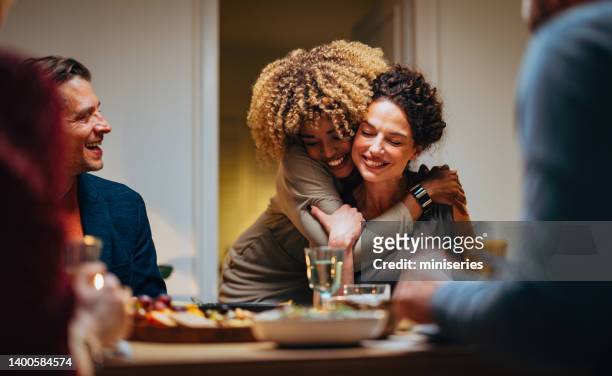 dos amigos abrazados durante una cena de celebración - vida doméstica fotografías e imágenes de stock