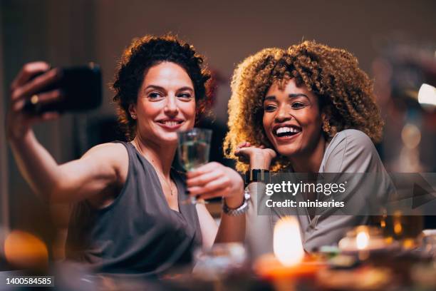 zwei freundinnen, die während einer dinner-feier für ein selfie posieren - dinner party menschen raum elegant stock-fotos und bilder