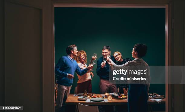 glückliche freunde, die während einer dinner-feier mit einem glas wein anstoßen - group wine stock-fotos und bilder