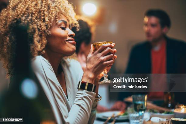 glückliche frau genießt ein glas wein während eines abendessens mit freunden - woman holding champagne stock-fotos und bilder