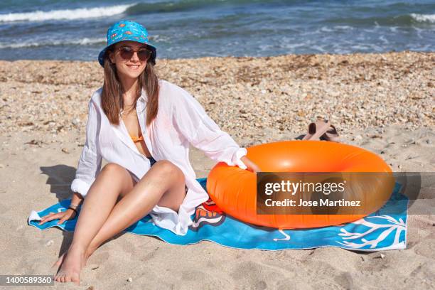 girl on the beach with an orange float sitting on a beach towel - toalla stock pictures, royalty-free photos & images