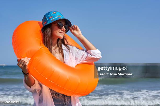 portrait of a girl with an orange float on a beach in summer clothes - hot spanish women fotografías e imágenes de stock