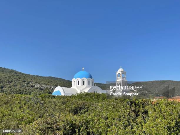 the church of agioi anargyroi through the bushes, skala, agistri, attica, greece - skala greece fotografías e imágenes de stock