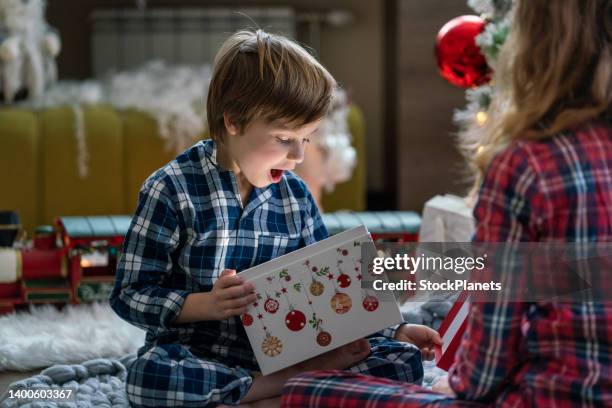 überraschter kleiner junge beim öffnen des weihnachtsgeschenks - boy in a box stock-fotos und bilder