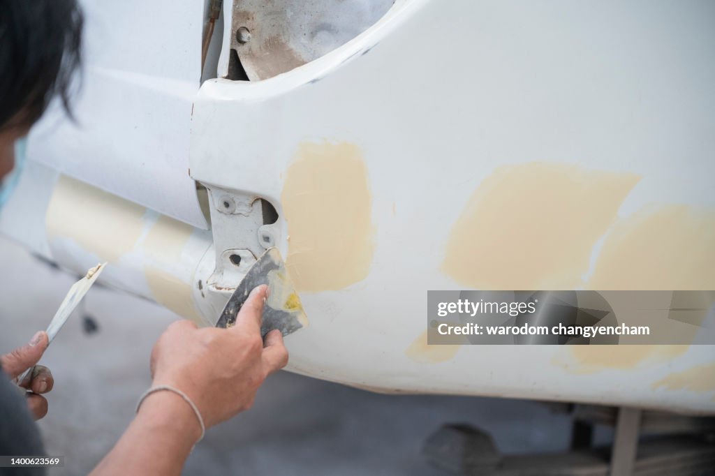 Workers fix car paint with putty.