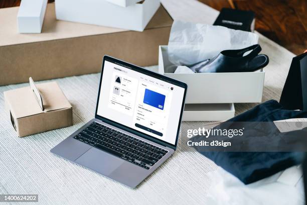 high angle shot of online shopping purchase with laptop and making mobile payment online with credit card, with shopping packages and delivery boxes laying out around. online shopping and e-commerce. contactless payment. new shopping habits and routine - online shopping stock pictures, royalty-free photos & images