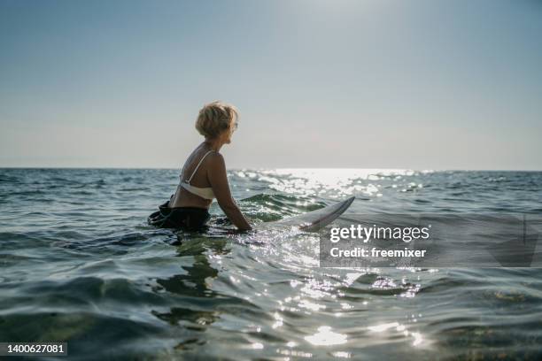 female surfer in the sea - older woman bathing suit stock pictures, royalty-free photos & images