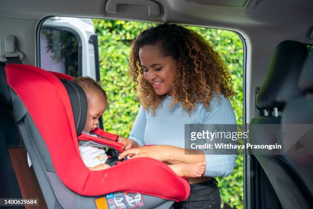shot of an adorable little girl being secured in her car seat by her mother - fasten stock pictures, royalty-free photos & images