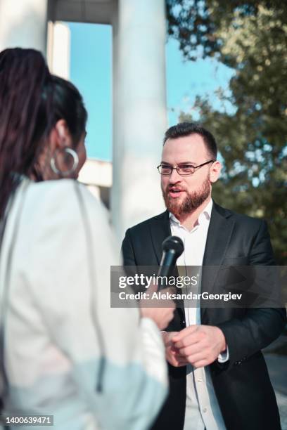 male politician explaining program during live broadcast from city park - microphone press conference stock pictures, royalty-free photos & images