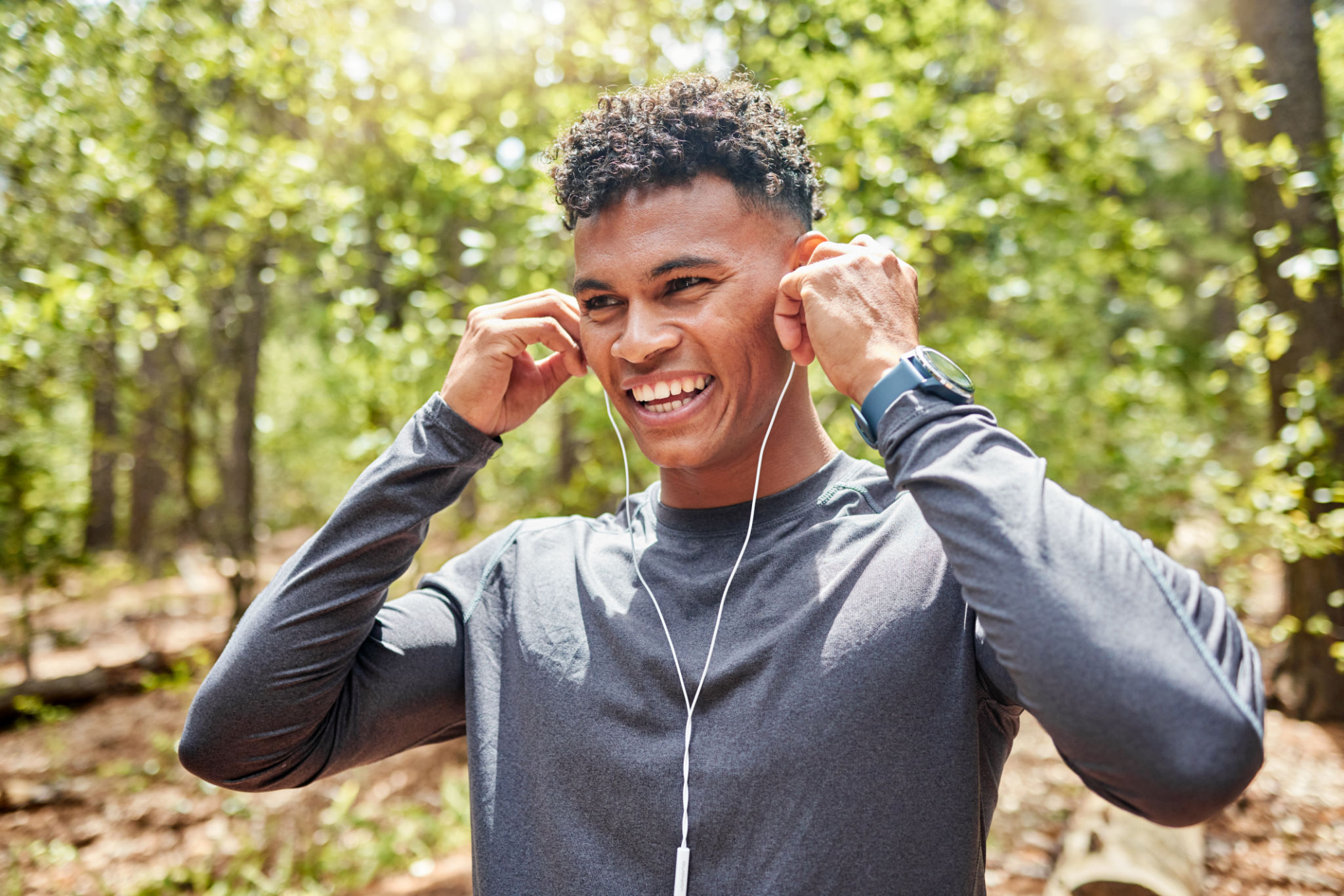 Young mixed race hispanic fit male athlete listening to music while on a run in a forest outside in nature. Exercise is good for health and wellbeing. Enjoying, positive, happy Young mixed race hispanic fit male athlete listening to music while on a run in a forest outside in nature. Exercise is good for health and wellbeing. Enjoying, positive, happy