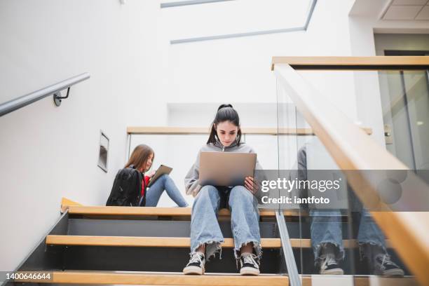 girl sitting on the high school stairs studing with laptop. - schoolkinderen stockfoto's en -beelden