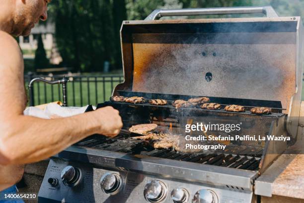 man cooking hamburger on grill - burgers cooking grill stockfoto's en -beelden