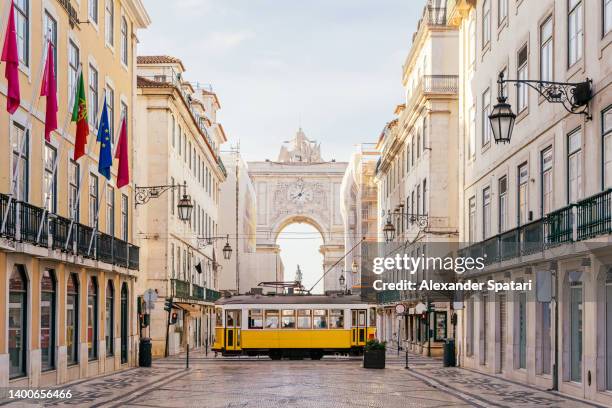 rua augusta arch and yellow tram in lisbon, portugal - lissabon stockfoto's en -beelden