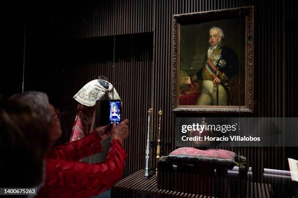Visitor photographs a crown and a king's portrait at the Royal Treasure Museum in Ajuda National Palace on June 02, 2022 in Lisbon, Portugal. The...
