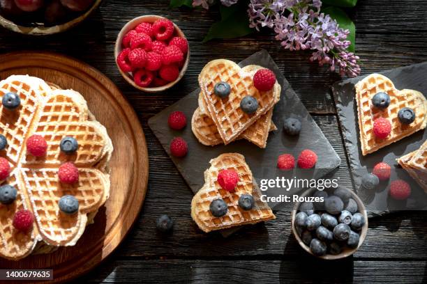 waffeln mit beerenfrüchten auf dunklem holztisch - waffeln stock-fotos und bilder