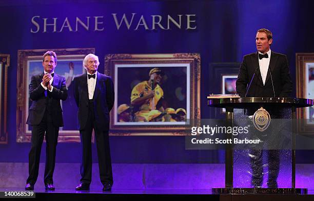 Shane Warne of Australia is watched by Richie Benaud and Mark Nicholas after being inducted into the Australian Cricket Hall of Fame during the 2012...
