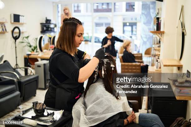 hairdresser dyeing client's hair. - peluquero fotografías e imágenes de stock