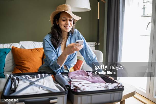 portrait of woman wearing straw hat and packing for a trip - women reservation stock pictures, royalty-free photos & images