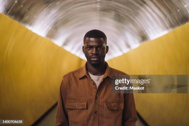 portrait of serious young man standing in tunnel - staring stock pictures, royalty-free photos & images