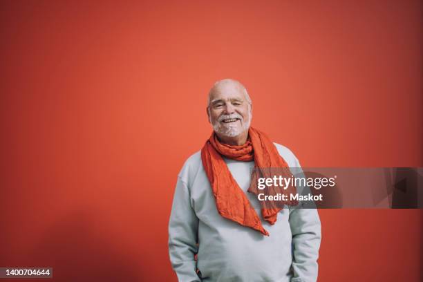 portrait of happy senior man standing against orange background - senior adult man stock pictures, royalty-free photos & images