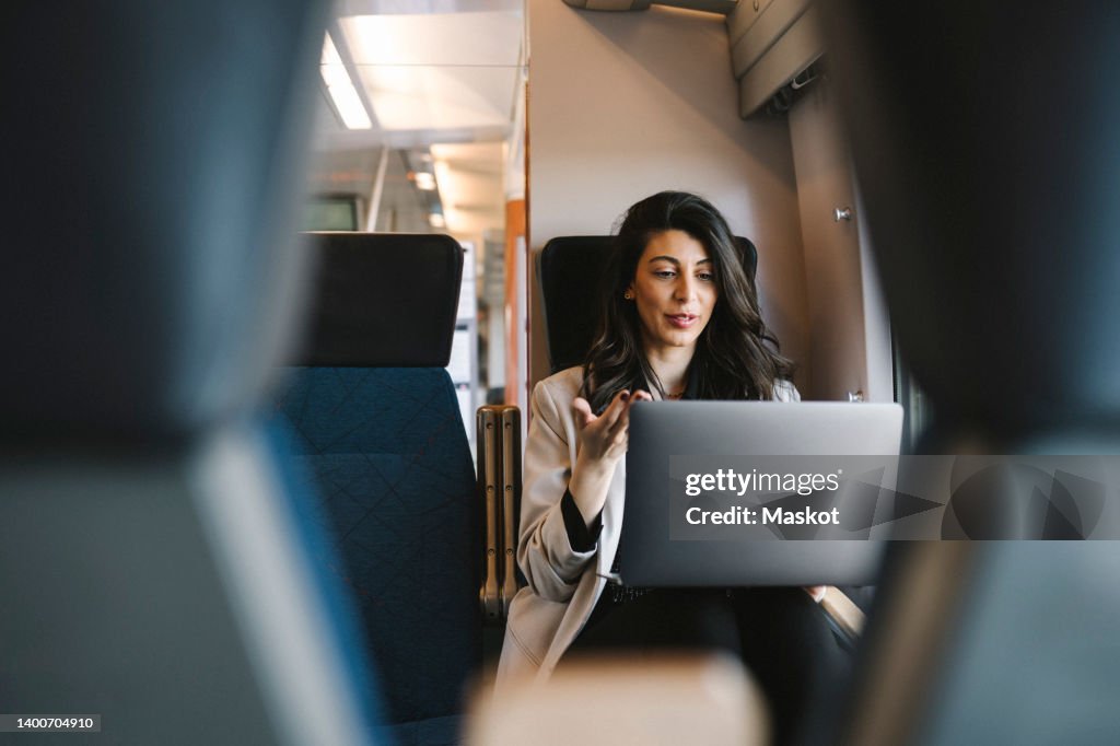 Businesswoman talking on video call through laptop while sitting in train