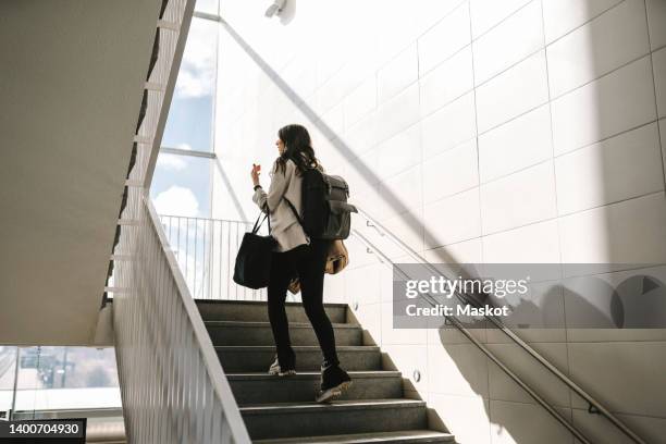 rear view of businesswoman with backpack moving up on staircase at railroad station - degraus e escadas - fotografias e filmes do acervo