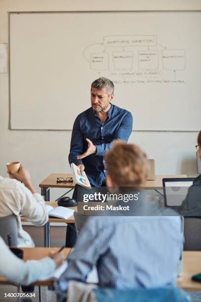 male teacher gesturing while teaching students classroom - white male professor foto e immagini stock