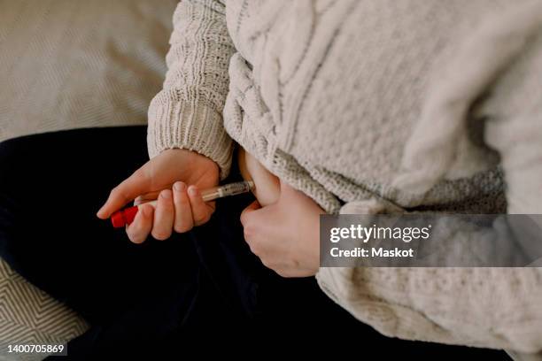 midsection of lesbian woman injecting syringe in abdomen during ivf test at home - injecting foto e immagini stock