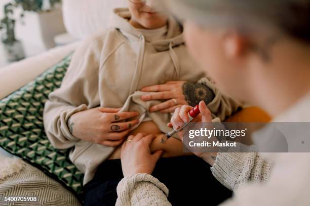 lesbian women doing ivf test with syringe at home - woman injecting stock pictures, royalty-free photos & images