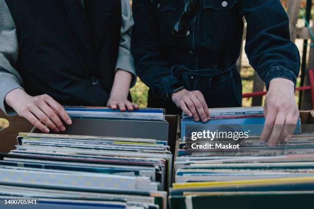 midsection of gay women selecting record at market stall - plattenladen stock-fotos und bilder