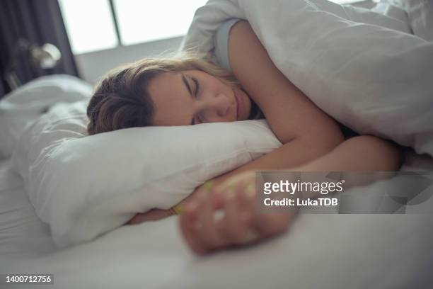 a beautiful woman sleeps on the white sheets of a hotel room. - sleeping bildbanksfoton och bilder