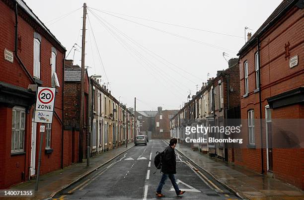 Pedestrian passes both occupied and boarded-up residential properties in Liverpool, U.K., on Friday, Feb. 24, 2012. U.K. House prices held their...