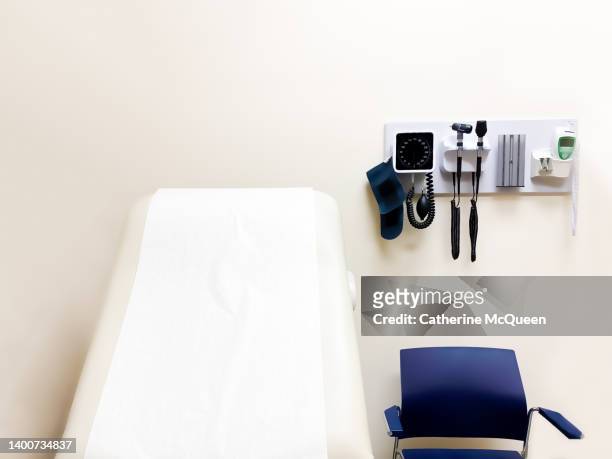 access to medical care: wall-mounted medical diagnostic equipment beside standard patient examination chair - vårdcentral bildbanksfoton och bilder