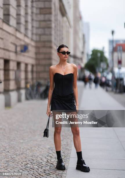 Celine Bethmann wearing Balenciaga black shades, Jacquemus black bag, Prada black loafer, vintage black mini dress on May 31, 2022 in Berlin, Germany.